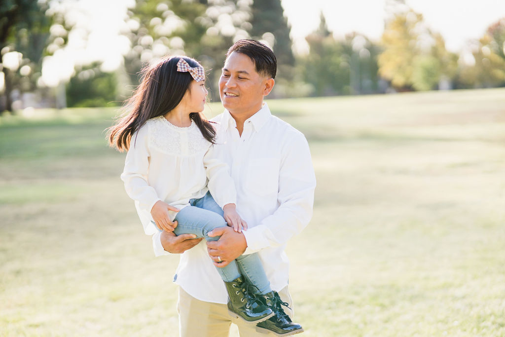 dad holding his daughter in front of grassy field