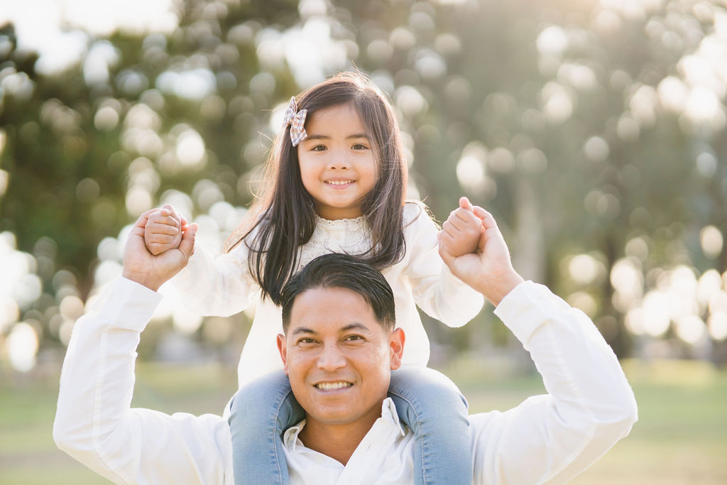 little girl sitting on her father's shoulders